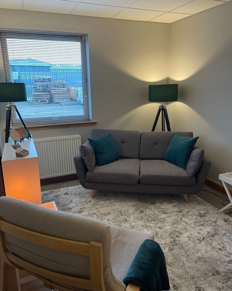 A quiet corner of the counselling room with an armchair and soft lighting